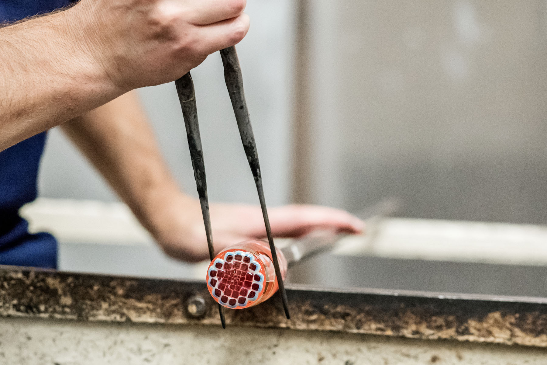 Making the Millefiori using patterns assembled from hot threads pulled from the molten material drawn from the mouth of the pots in the furnace. 